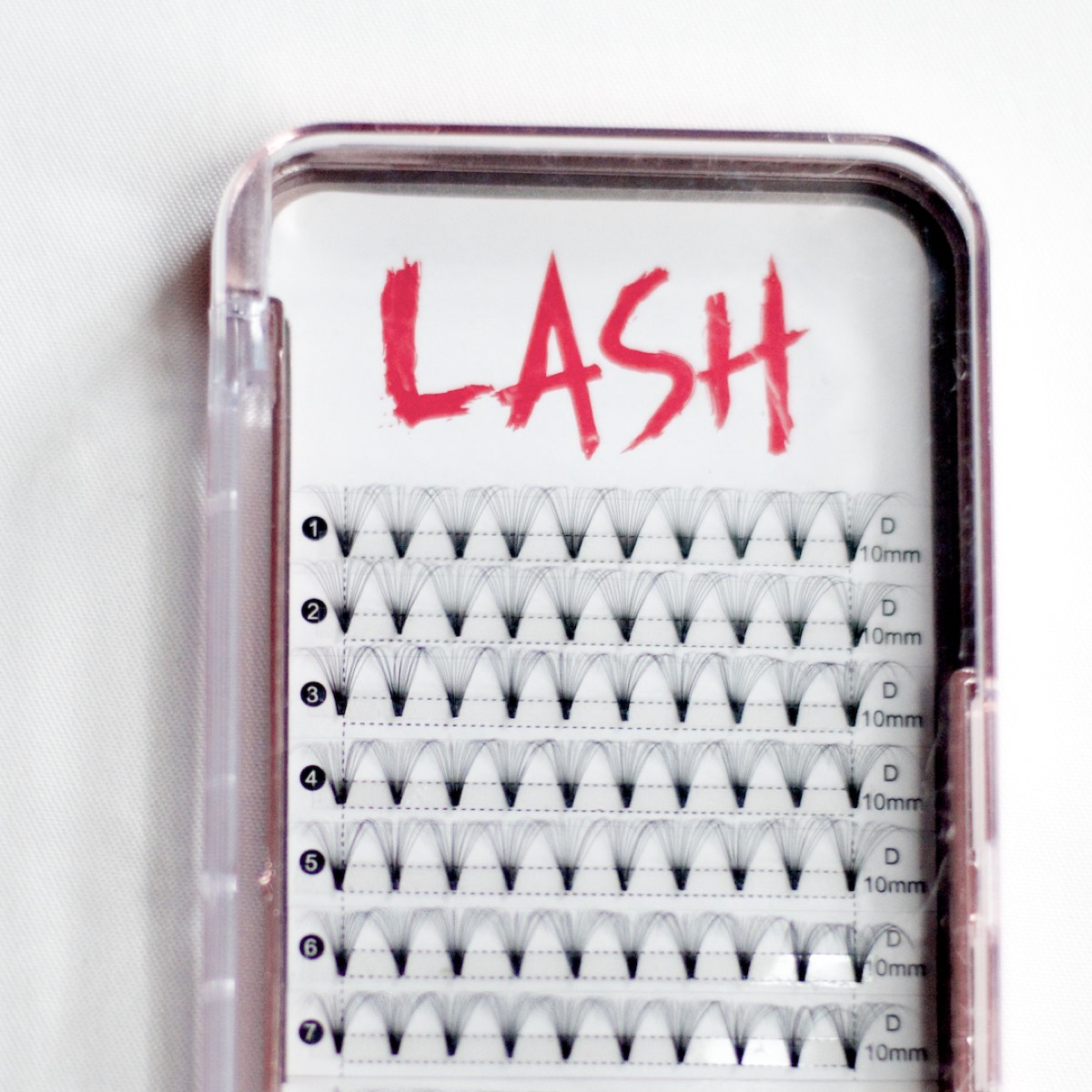 An open clear tray of eyelash extension fans in seven numbered rows, each row marked D 10mm, under a red brush-lettered LASH wordmark