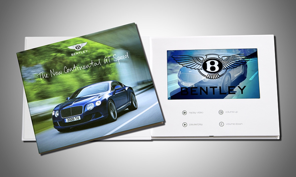 A Bentley Continental GT Speed brochure lying open, a video screen built into the right-hand page